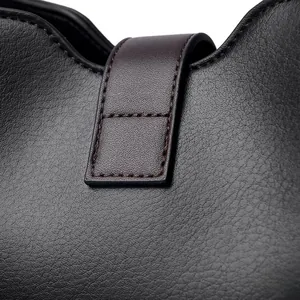 Détail du sac seau en cuir noir grainé avec bride marron et surpiqûres de précision