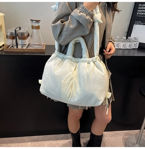 Detail of a creamy white quilted puffer bucket bag with adjustable drawstring closure
