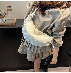 Detail of white pleated dumpling bag featuring drawstring closure and nylon texture