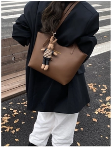 Brown leather tote bag detail with brown rabbit plush charm on female model