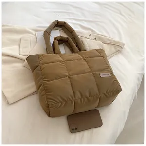 Detailed view of caramel quilted puffer tote bag with fashion patch on casual outfit