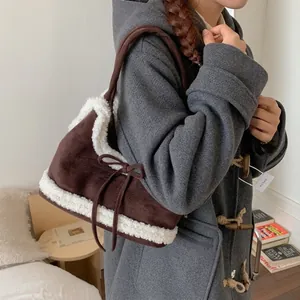 Brown suede tote bag with white fleece trim and a large bow shown on a shoulder