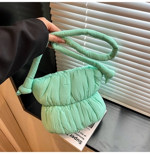 Detail of mint green puffy cloud bag with soft quilted texture and knotted handle strap