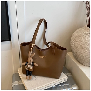 Detail of dark brown leather tote bag with a cute rabbit charm on a stylish travel case