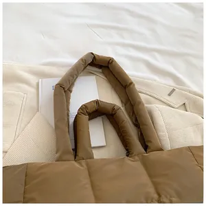 Detail of coffee brown quilted tote bag with soft padded handles on neutral bedding