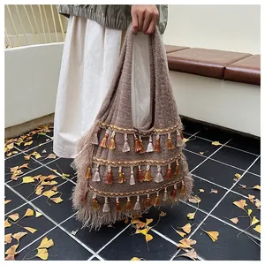 Detail of bohemian knitted tote bag with multi-color fringe and soft tassel textures