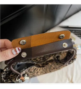 Detail of leopard print tote bag with brown faux leather handles and silver snap button