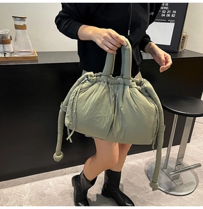 Detail of sage green quilted bucket bag featuring drawstring closure and soft nylon texture