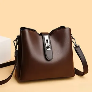 Détail du sac seau en cuir marron foncé avec boucle argentée et bandoulière réglable