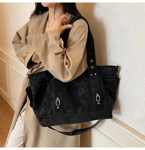 Close-up of a large black tote bag featuring metal rings and side pockets for daily use