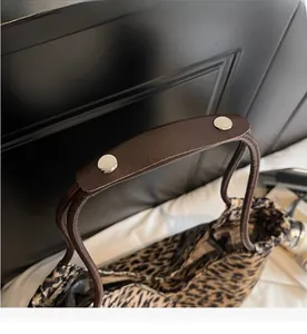 Close-up of leopard print canvas tote bag with durable brown leather handles and rivets