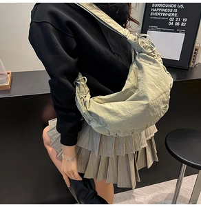 Model wearing a khaki pleated crescent bag with adjustable strap and large capacity