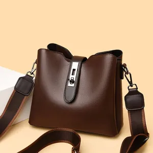 Détail du sac seau en cuir marron foncé avec bandoulière rayée et boucle argentée