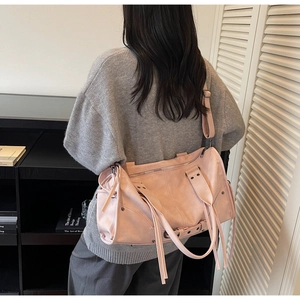 Model wearing a pale pink wasteland style tote bag with fringe and rivet details