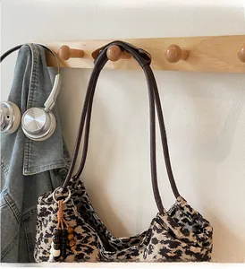 Detail of leopard print canvas tote bag featuring wooden bead charm and sturdy handle