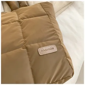 Detail of warm brown quilted tote bag showing puffy texture and fashion leather patch