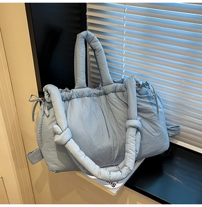 Close-up of light blue quilted tote bag with soft knot handle on wooden table
