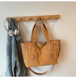 Detail of yellow canvas tote bag with side pockets and metallic rivet accents