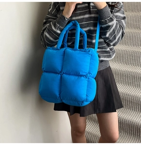 Detail view of the electric blue quilted puffy bag with square stitching and soft texture