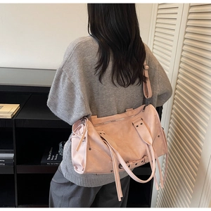Rear view of a pink shoulder bag with long tassel charms and an adjustable strap