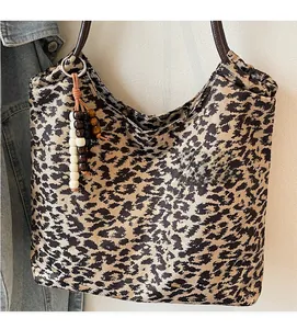 Close-up of leopard print tote bag with brown straps and bohemian wooden bead charm