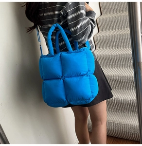 Lifestyle shot of large blue quilted puffer tote bag with top handle and strap