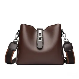 Détail du sac seau marron foncé avec fermoir rotatif en argent et texture cuir grainé mat