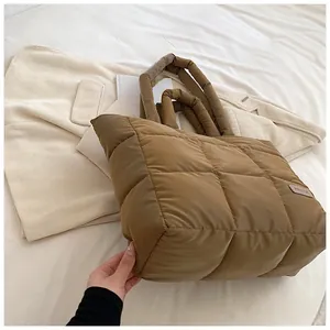 Macro detail of brown quilted puffer tote bag with quilted texture and fashion tag