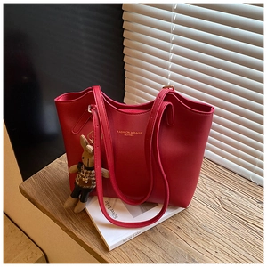 Detail of red leather tote bag with gold lettering and cute bunny charm accessory