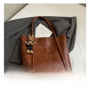 Close-up of brown leather bucket bag with decorative button and cute rabbit doll keychain