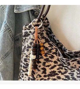 Detail of wooden bead charm with metal clasp on leopard tote bag for fashion decoration