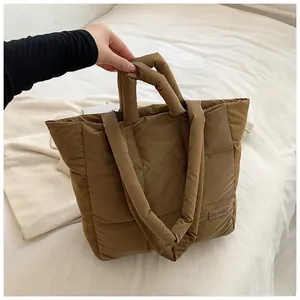Detail showing brown quilted padded tote bag texture with brown leather fashion label