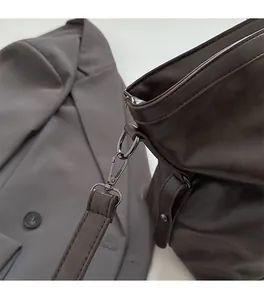 Gros plan du fermoir en métal et de la bandoulière en cuir sur le sac fourre-tout