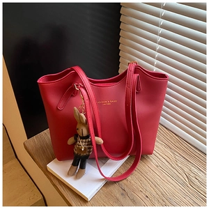 Macro shot of red faux leather tote bag texture with gold lettering and rabbit charm