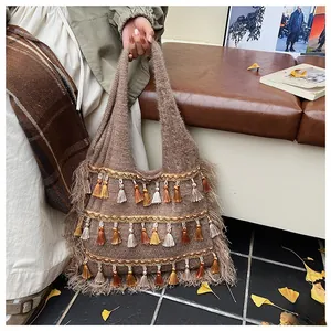 Detail of bohemian knitted tote bag with multi-colored fringe and warm autumn aesthetic