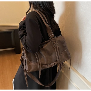 Side view of large vintage dark brown leather shoulder bag with tassels and rivets