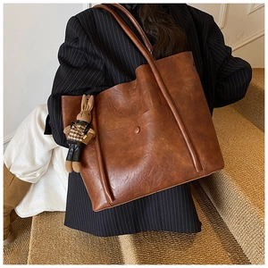 Brown vintage tote bag with rabbit charm shown on a model in a cozy staircase setting