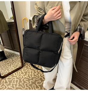 Detail of black quilted puffer tote bag featuring padded square design and adjustable strap