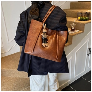 Large brown tote bag featuring a cute plush bunny charm and thin shoulder straps
