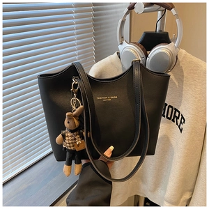 Detailed view of black leather tote bag with gold lettering and cute plush rabbit charm