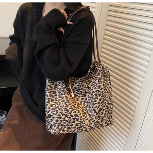 Detail of leopard print canvas tote bag with brown straps and wooden bead pendant accessory