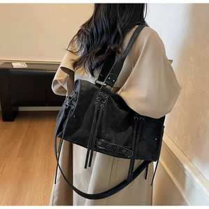 Detail of black punk shoulder bag with metal buckles and drawstrings in a modern setting