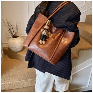 Detail of dark brown tote bag with vintage texture and cute rabbit plush pendant