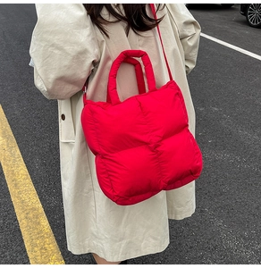 Outdoor street shot of a red puffer tote bag paired with a classic beige trench coat