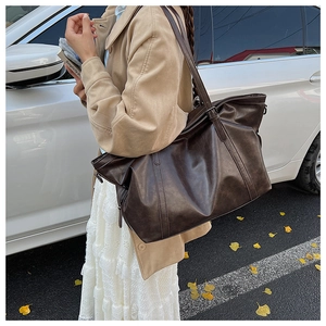 Detail view of large vintage brown leather tote bag with side zipper and long straps