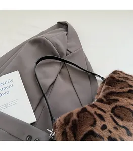 Detail of leopard print faux fur shoulder bag with leather strap on grey blazer