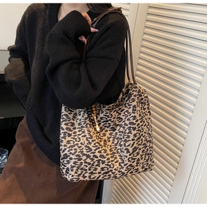 Detail of leopard print tote bag with brown leather straps and wooden bead accessory