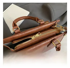 Close-up of brown leather bag showing gold zipper detail and smooth top opening