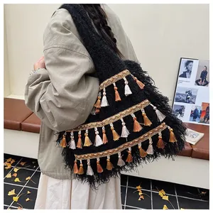 Detail of black knit tote bag with golden woven bands and multi-colored fringe tassels