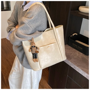 Close-up of minimalist tote bag in cream faux leather with decorative rabbit pendant